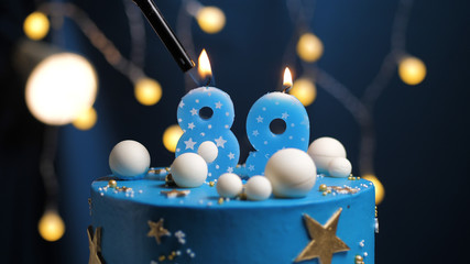 Birthday cake number 89 stars sky and moon concept, blue candle is fire by lighter. Copy space on...