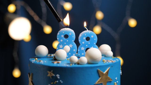 Birthday cake number 88 stars sky and moon concept, blue candle is fire by lighter. Copy space on right side of screen. Close-up