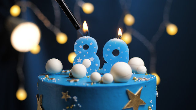 Birthday cake number 89 stars sky and moon concept, blue candle is fire by lighter. Copy space on right side of screen. Close-up