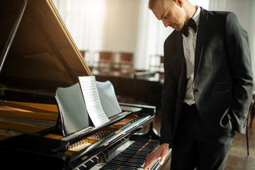 talented young caucasian pianist man practicing, perform awesome music. musician in formal elegant...