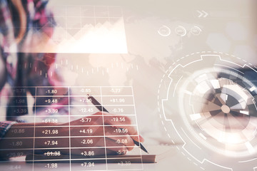 A woman hands writing information about stock market in notepad. Forex chart holograms in front. Concept of research. Double exposure