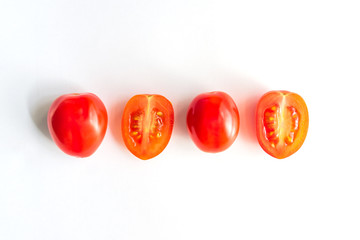 Ripe red cherry tomatos in a row. Whole and halves of vegatbles on white background