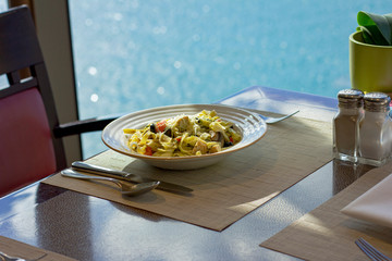 Pasta with meat on a white plate. Restaurant overlooking the sea.
