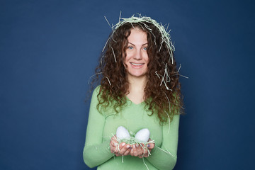 Happy Easter female has overjoyed facial expression, presents mock up eggs for someone, has joy,...