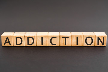 Naklejka premium Addiction - word from wooden blocks with letters, an inability to stop doing or using something addiction concept, black background