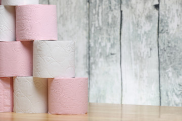 A stack of pink and white toilet paper on a table on a wooden background