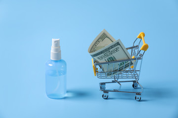 Dollar bills roll in shopping cart and hand sanitizer on shopping. Concept of hoard, buy or...