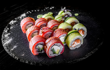 set of sushi roll with tuna, avocado, cream cheese, cucumber, rice in plate on black wooden table background