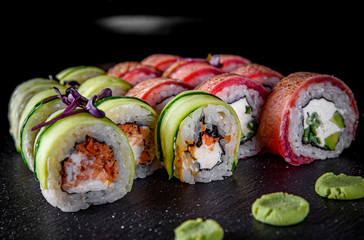 set of sushi roll with tuna, avocado, cream cheese, cucumber, rice in plate on black wooden table background