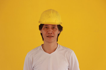 Male civil engineer with yellow helmet and wear white T-shirt on yellow background.