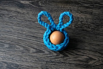 Obraz na płótnie Canvas handmade crochet turquoise Easter basket with egg on wooden background