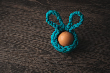 Obraz na płótnie Canvas handmade crochet turquoise Easter basket with egg on wooden background