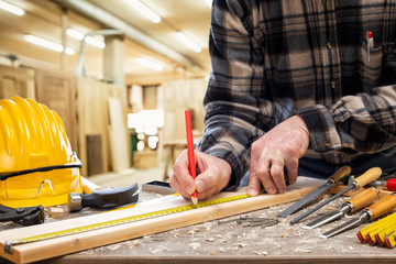 Close-up. Carpenter with pencil and the meter marks the measurement on a wooden board. Construction...