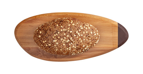 Isolated whole bread with seeds and flakes on wooden oval cutting board on white background.