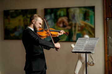 handsome talented violinist in suit play on classic musical instrument, before performance. elegant...