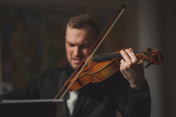 handsome caucasian guy with classic instrument violin, talented male musician in theatre practice before performance