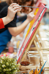 art school, creativity and people concept - woman with  brush painting at studio