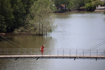 Fototapeta premium A woman standing on a wooden walkway at Rak samae Bridge in Rayong, Thailand