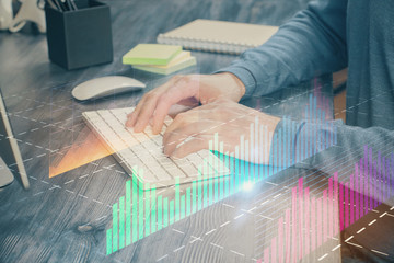 Stock graph with businessman typing on computer in office on background. Concept of analysis. Double exposure.