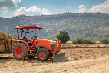 Obraz premium tractor in agriculture field with mountain and blue sky