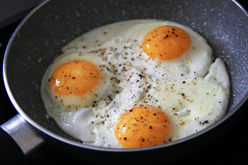 three baked eggs in frying pan