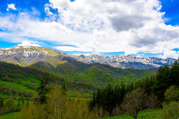 Beautiful mountain panorama with lush greens, blue skies, and puffy clouds