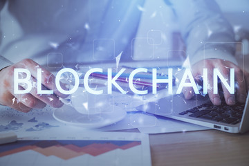 Crypto currency theme hologram with businessman working on computer on background. Concept of blockchain. Double exposure.