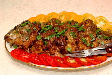 Fried carp with beer and cookies on a plate, decorated with red and yellow tomatoes, Old Czech fish recipe