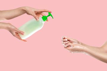 Concept of disinfection and protection from viruses.Women's hands are washed with soap at the bottom, and women's hands with antibacterial liquid soap at the top. Hands close-up.Pink background