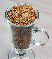 A glass of buckwheat - traditional Russian meal - on wooden background. Buckwheat deficit concept