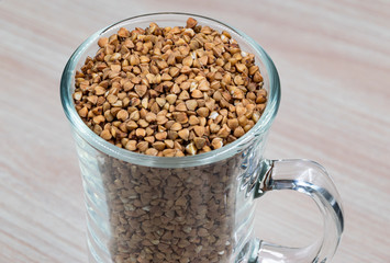 A glass of buckwheat - traditional Russian meal - on wooden background. Buckwheat deficit concept