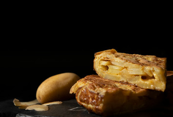 Typical spanish tapa. Spanish omelette front photography with black background.