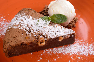 brownies sprinkled with slices of almonds and mint, stacked against an orange plate.