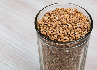 A glass of buckwheat - traditional Russian meal - on wooden background. Buckwheat deficit concept