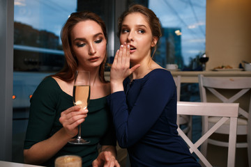 Two girls gossip in a cafe in the evening