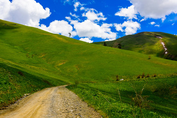 Beautiful mountain panorama with lush greens, blue skies, and puffy clouds