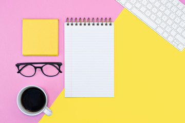 pink and yellow colorful desk table flat-lay textbook, writing. coffee, keyboard and glasses. spring. copy space 