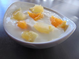 Yoghurt with citrus fruits in a bowl. Sour cream, yogurt with fresh orange and lemon, close up.