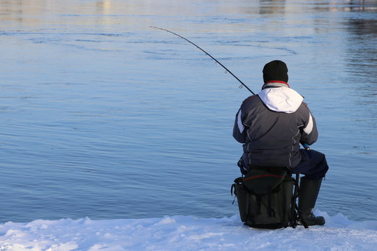 Winter fishing. Man fishing on the river bank