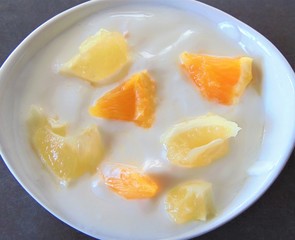 Yoghurt with citrus fruits in a bowl. Sour cream, yogurt with fresh orange and lemon, close up.