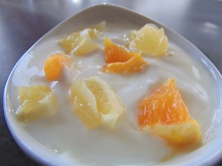 Yoghurt with citrus fruits in a bowl. Sour cream, yogurt with fresh orange and lemon, close up.