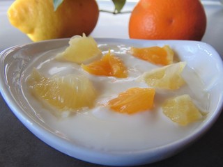 Yoghurt with citrus fruits in a bowl. Sour cream, yogurt with fresh orange and lemon, close up.