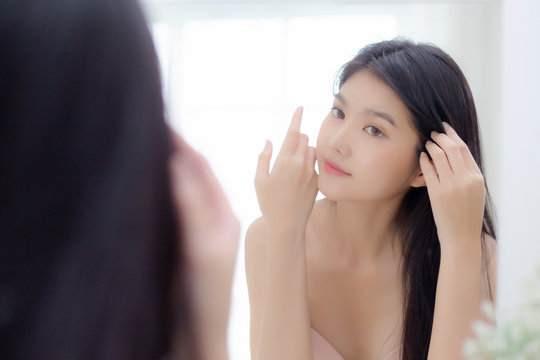 Beautiful Young Asian Woman Smiling Look At Mirror Of Touch Hair In The Room, Cosmetic For Hygiene Hair Care, Beauty Asia Girl Happy For Hairstyle Treatment At Home, Lifestyle And Makeup Concept.