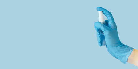 Fototapeta premium Hand in medical gloves with alcohol gel sanitizer on blue background