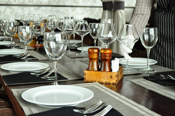 Wine glasses, appliances and plates on a wooden table in a restaurant. Interior