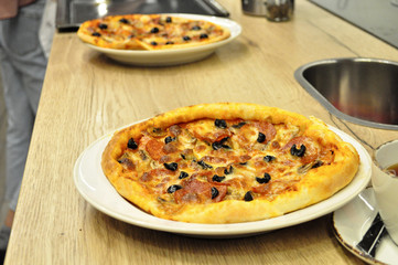 Pizza with cheese and tomatoes and olives on a white plate