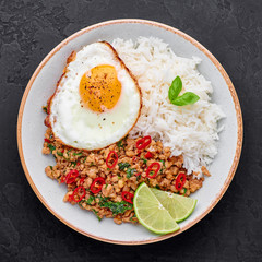 Pad Krapow Gai - Thai Basil Chicken with Rice and fried Egg black slate background. Pad Krapow is Thai cuisine dish with minced chicken or pork meat, basil, soy and oyster sauces. Thai Food.