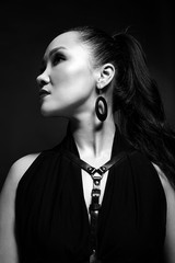 Noir black and white portrait of a girl with an Asian appearance, with expressive makeup, on a dark background.