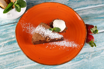 brownies sprinkled with slices of almonds and mint, stacked against an orange plate.