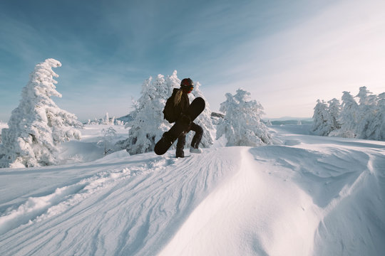 Portrait of snowboarder with board wearing mask in snowy winter landscape outdoors